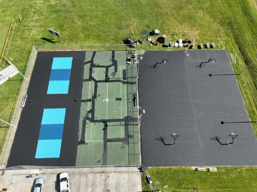 A drone shot shows an aerial view of two nearly completed pickleball courts while other sections of the complex remain under construction.