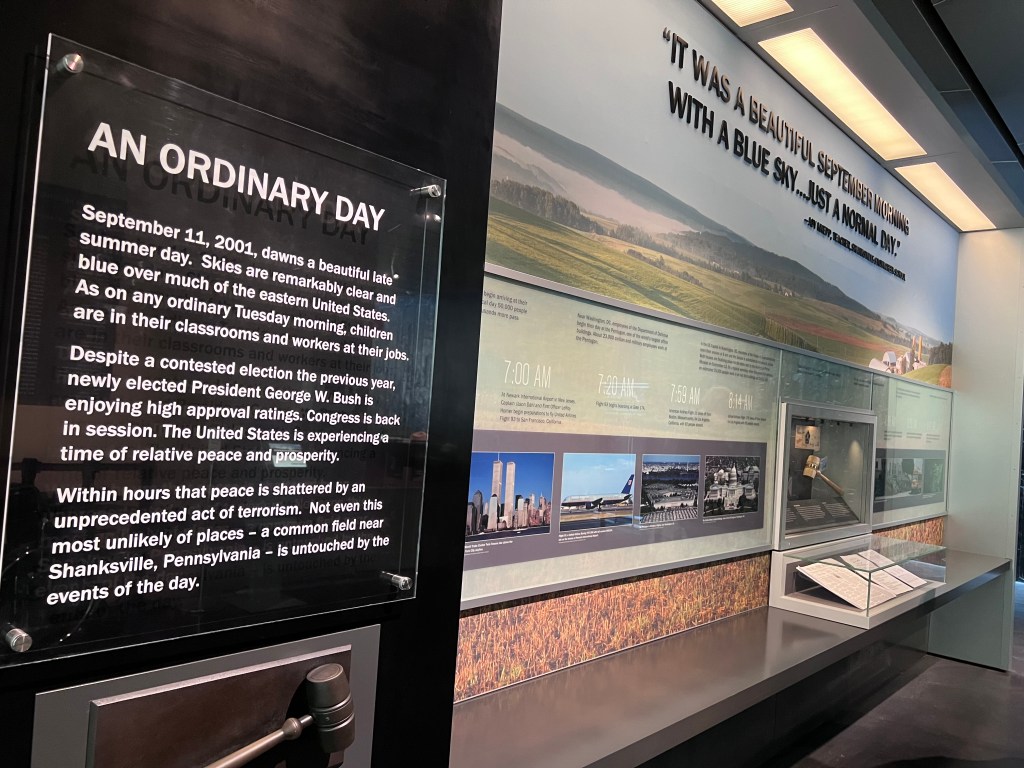 An exhibit wall inside the Flight 93 National Memorial Visitor Center. There is a timeline of events listed, and above the timeline reads:  "It was a beautiful September morning with a blue sky...just a normal day." 