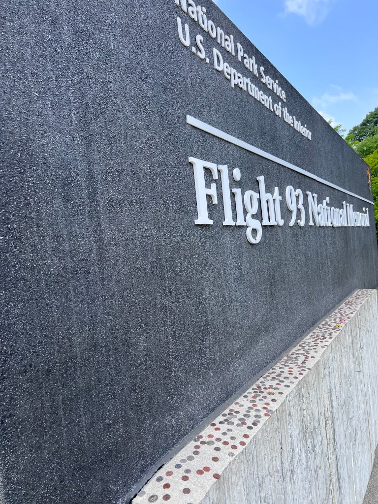 All types of coins are left on the concrete ledge of the Flight 93 National Memorial sign. 