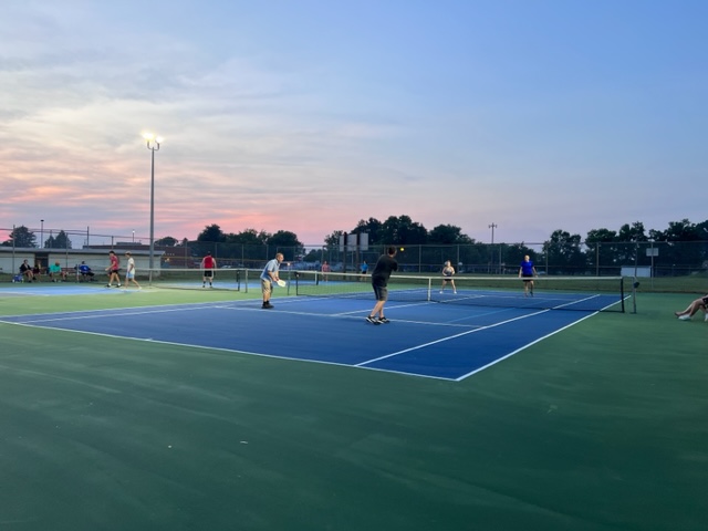 Four players utilize the tennis / pickleball combo court for a game.