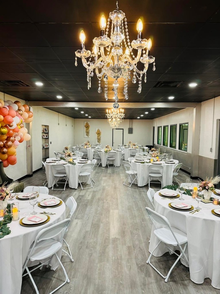A room is ready for an event, with matching table settings, balloons, flowers. 