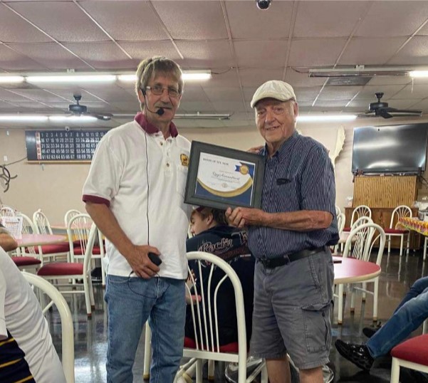 One man presents another with a framed award for "Moose of the Year." 