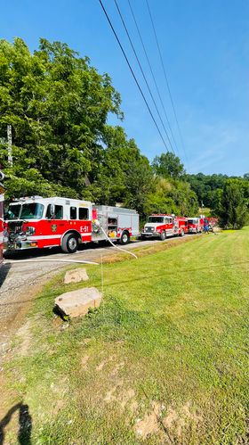 A line of several firetrucks parked near a fire.