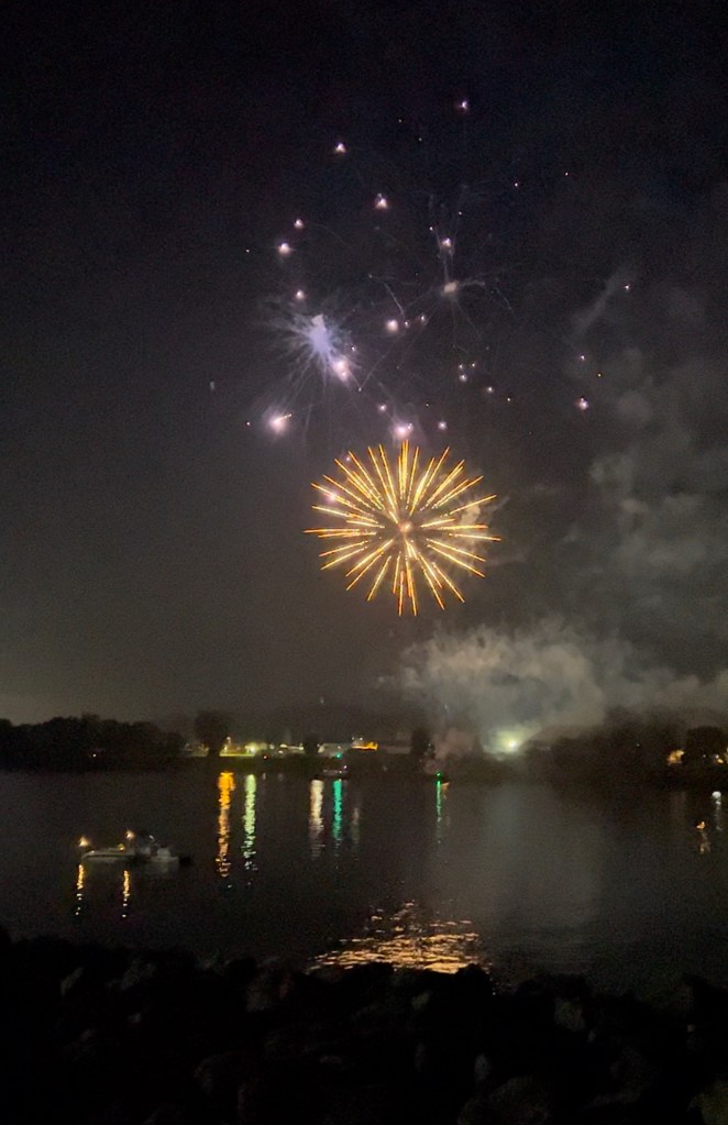 Fireworks light up the sky over the river.