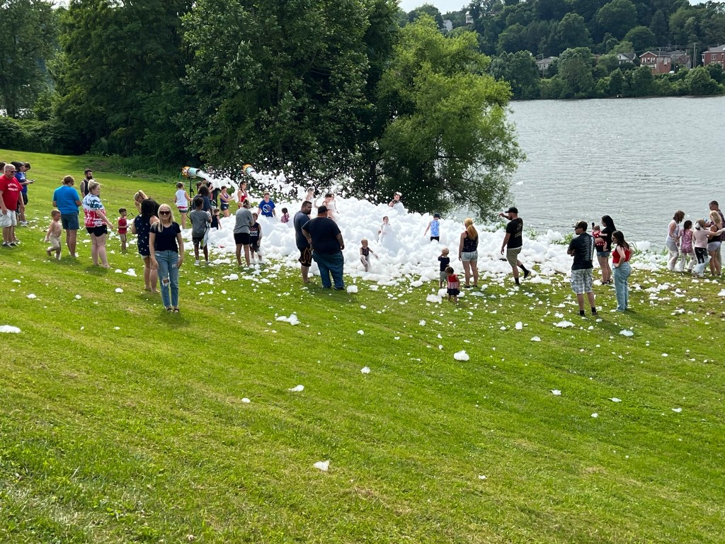 A large gathering of kids and parents in foam along the river.