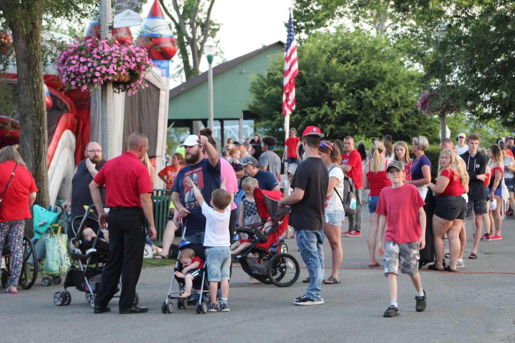 Several people gather in a park, there are several children near bounce houses. 