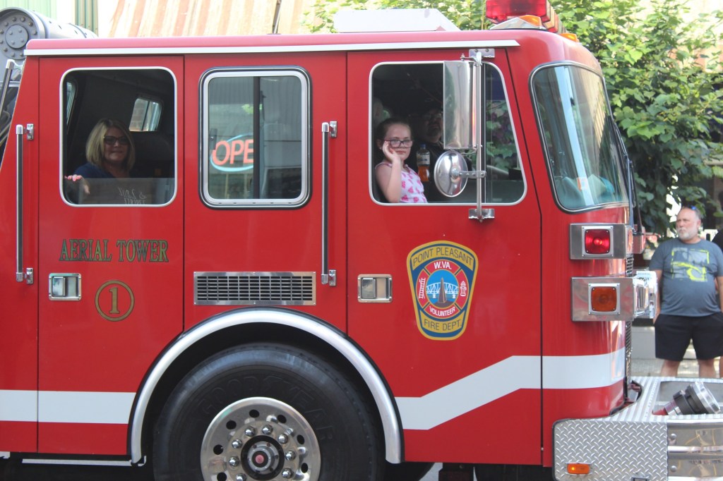 A young girl waves from the front seat of a firetruck from Point Pleasant Volunteer Fire Department. 