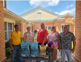 Four people stand behind bags of bird seed and other birding supplies.