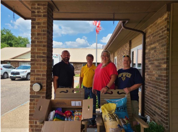Four people stand with bird seed and other supplies.