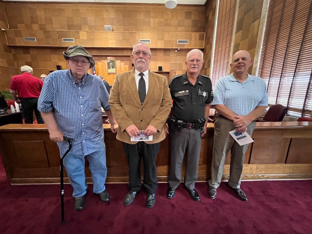 Four men stand in a line. They are former colleagues in law enforcement. 