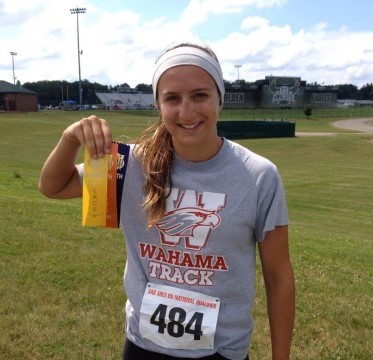 A track and field athlete holds up her ribbons.