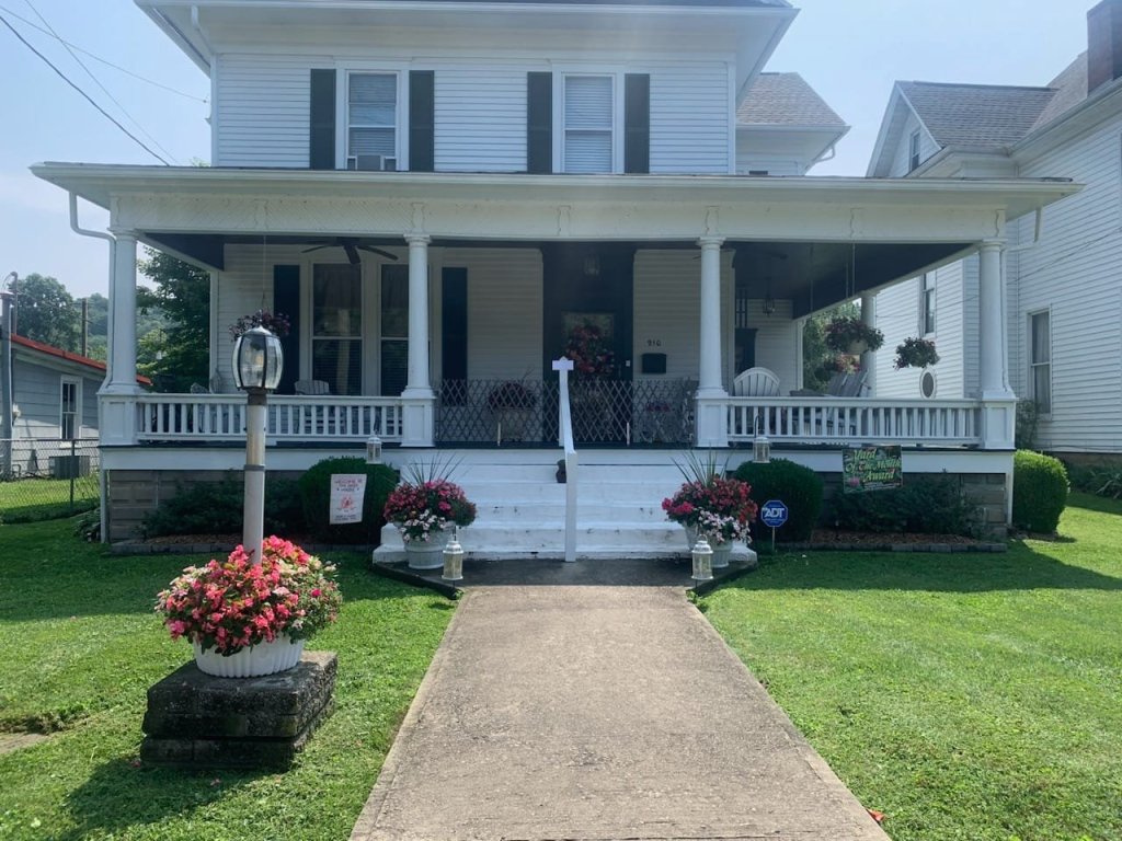 Pictured with a "Yard of the Month" sign, is a decorated yard, with flowers and landscaping surrounding a home. 