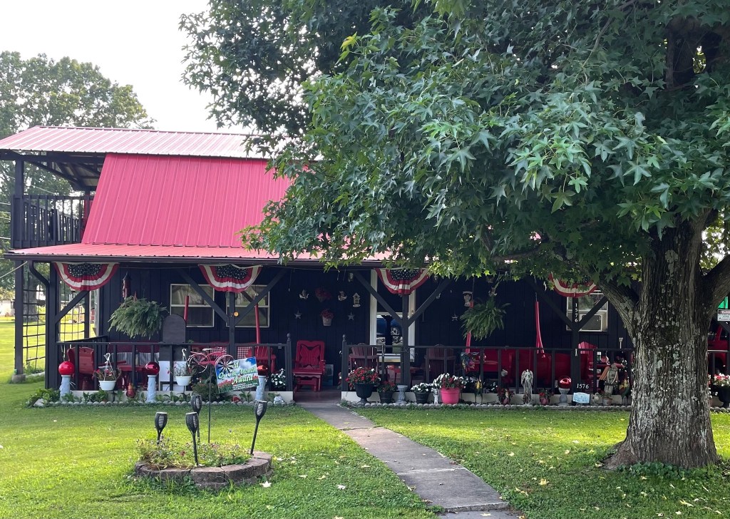 Pictured with a "Yard of the Month" sign, is a decorated yard, with flowers and landscaping surrounding a home. 