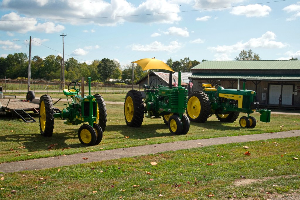 Three John Deere tractors sit side by side. 