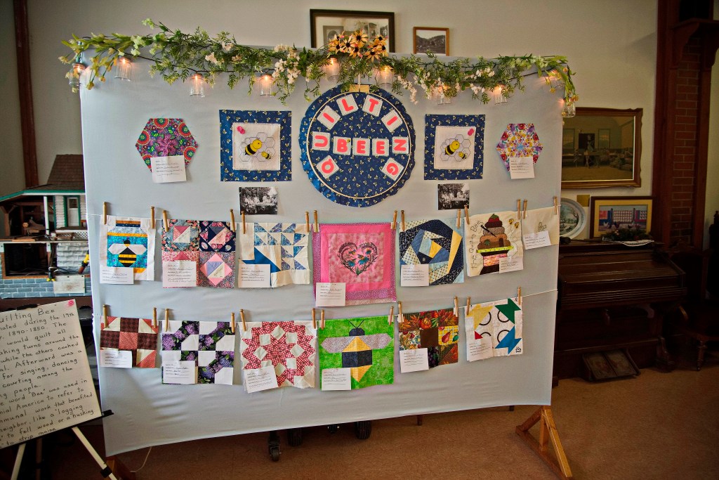 Individual quilt squares are displayed on a large canvas. 
