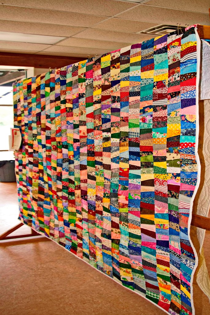 A large multi-color quilt is displayed. 