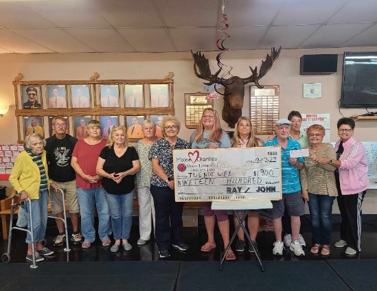 A group of 12 people stands in front of a large ceremonial check.