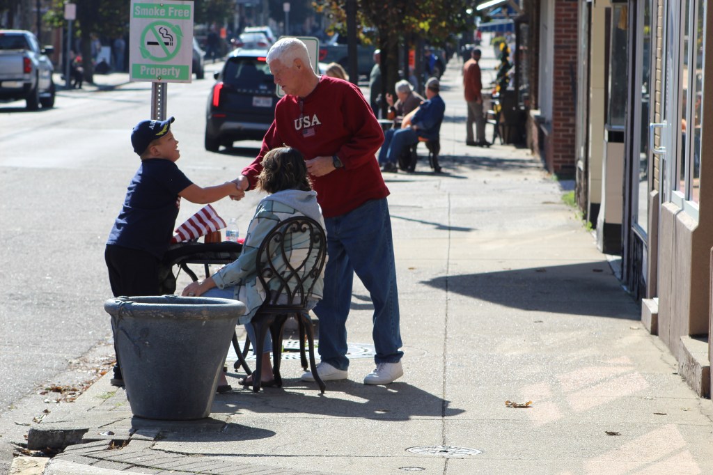 Parade goers greet each other on the sidewalk.