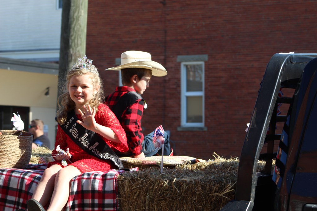 Young royalty waves from a float.